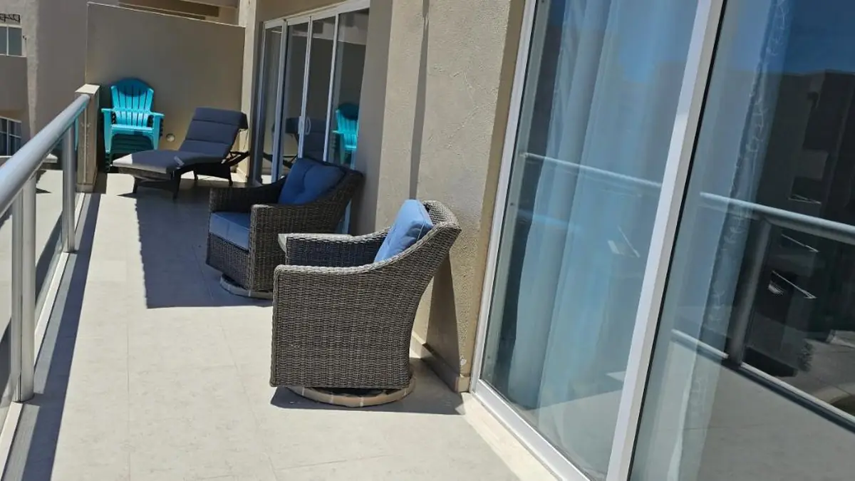 The apartment’s terrace with wicker armchairs, by the picture windows